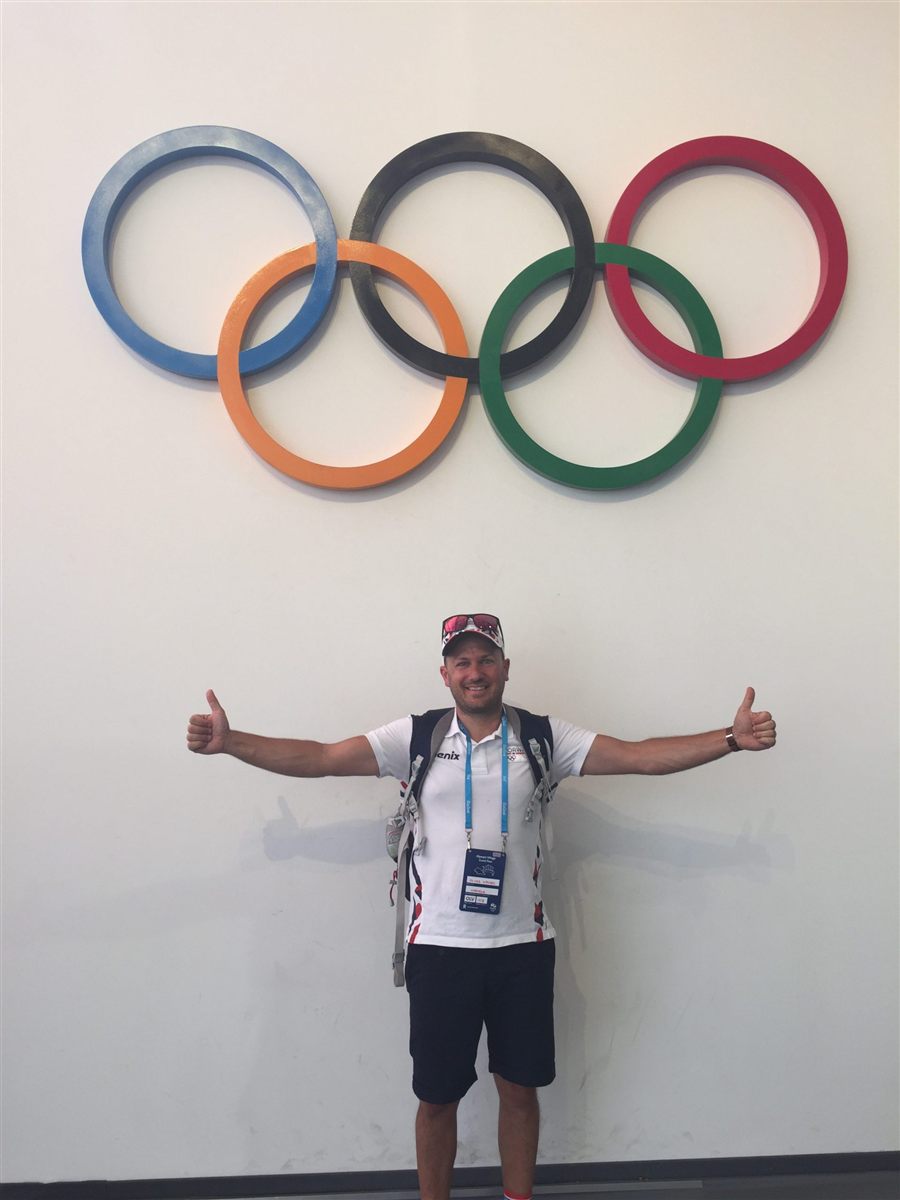 Oliver Wrobel in team clothing in front of the Olympic rings in the Olympic Village, Rio 2016