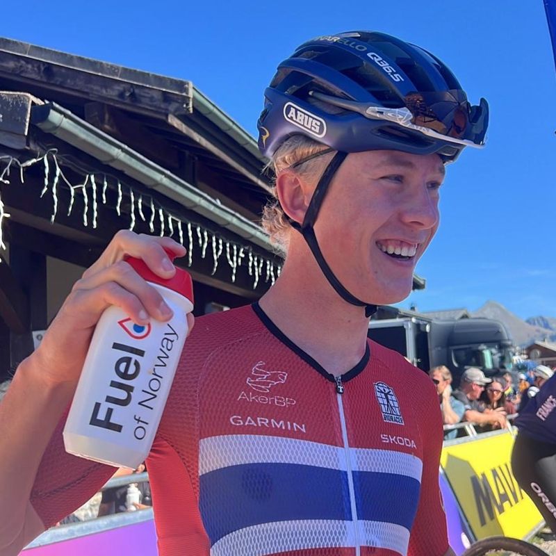 Smiling rider of the Norwegian national team in the partner jersey with a Fuel of Norway bottle